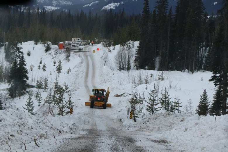 Heavy construction vehicles on a snowy pathway.