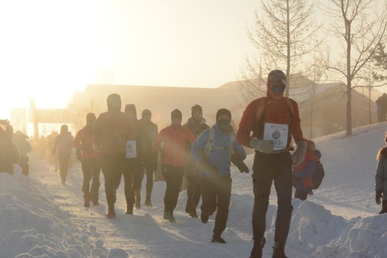 A group of people are seen running together on a cold winter's day.