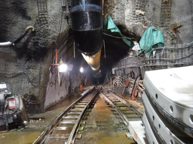 Tracks inside a dark tunnel with a boring machine in the distance