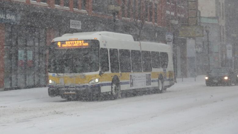 A city bus drives down a snowy urban street.