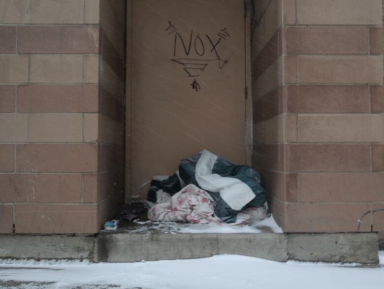 A pile of blankets gathers snow inside a doorway in downtown Hamilton.