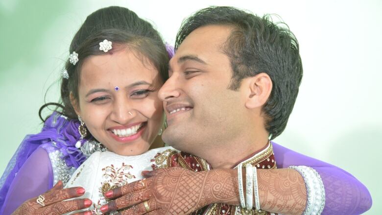 A young couple embrace while wearing traditional Indian attire on their wedding day. 