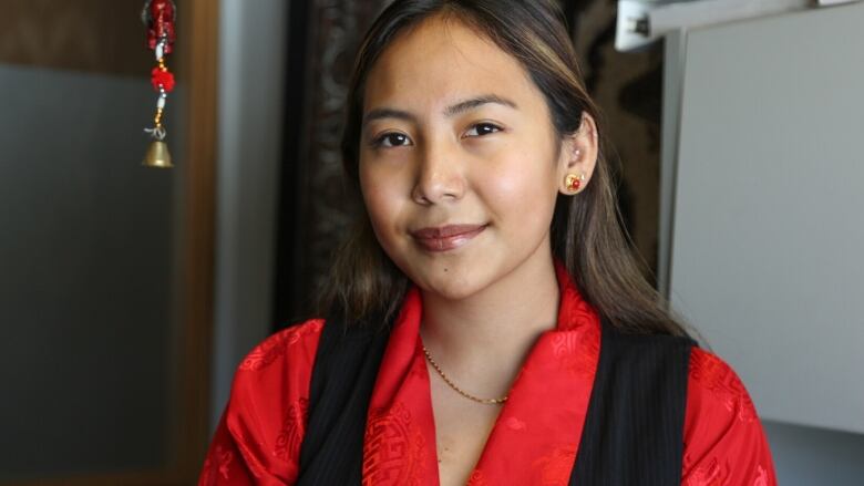 Chemi Lhamo is shown smiling at the camera, wearing red and black.