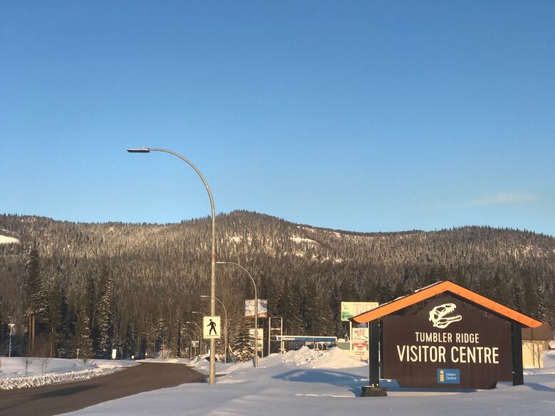 A town sign reading 'Tumbler Ridge Visitor Centre' with a dinosaur above it.