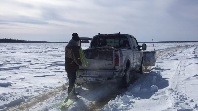 A pickup truck stalled on a winter road with a person standing behind it.