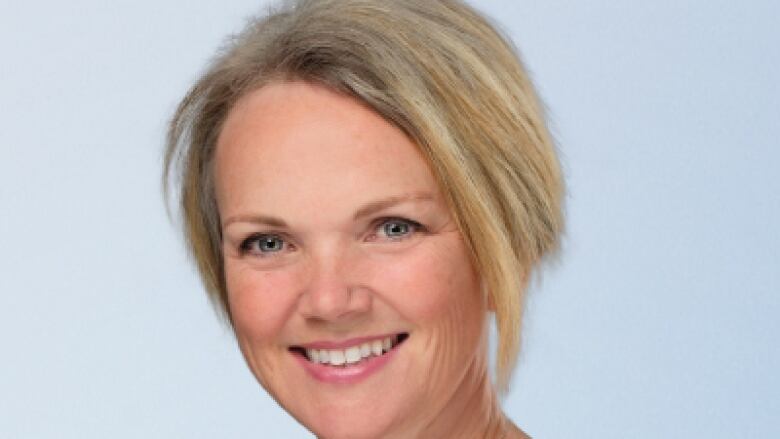 Smiling woman in black shirt with short blonde hair. 