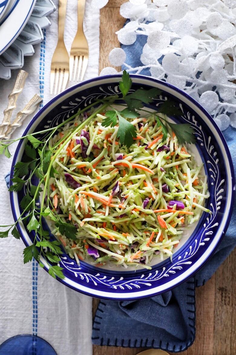 Overhead shot of a blue bowl of broccoli walnut slaw on a table with blue and white decor.