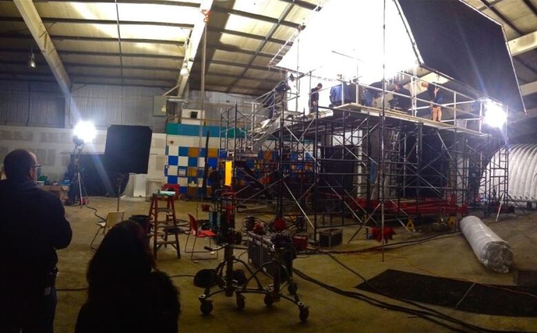 Lights and scaffolding for a film shoot are set up inside an old arena.