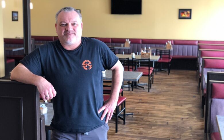 A man wearing a shirt with an 'IPC' logo stands in an empty diner.