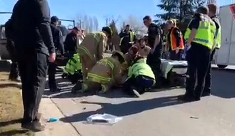 Firefighters and paramedics gather around an injured RCMP officer lying on a roadway.