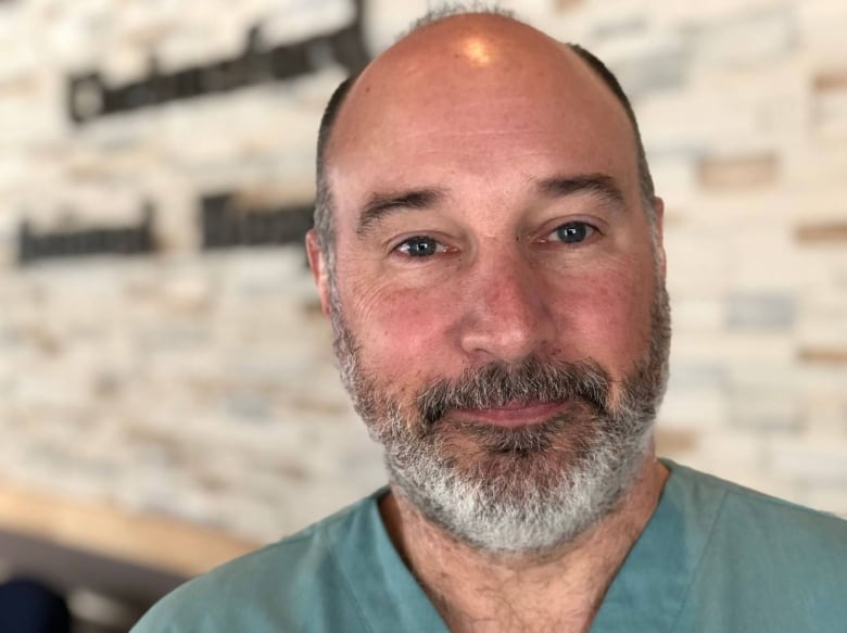 Man smiling into camera wearing scrubs 