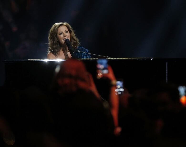 A woman sits at a piano