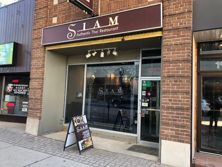 A brick building adorned with a brown sign that reads 'Siam Authentic Thai Restaurant.'