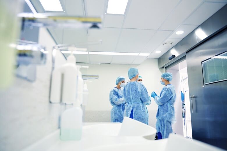 A group of surgeons in an operating room at a hospital talk and prepare to operate.