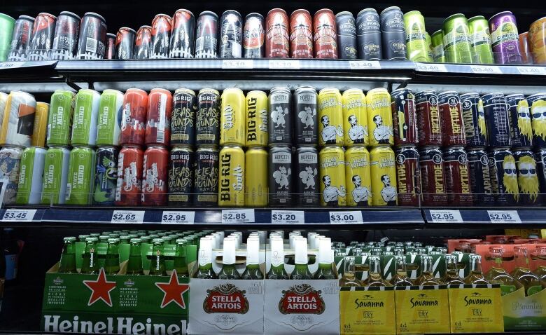 A row of shelves with beer cans and bottles.