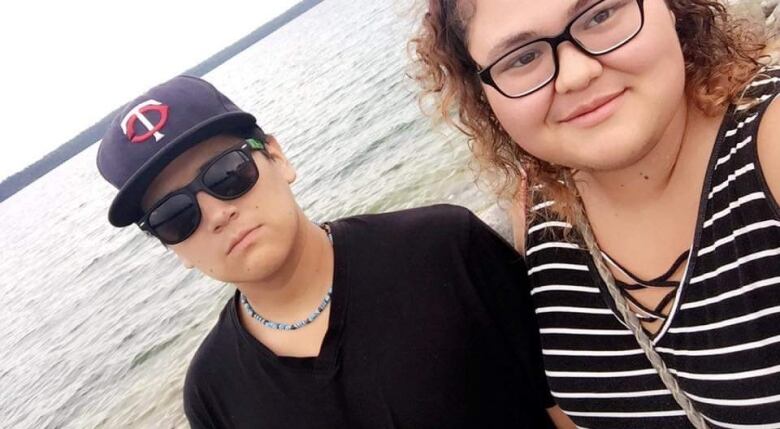 A teenage boy and girl are pictured posing for a selfie in front of a lake.