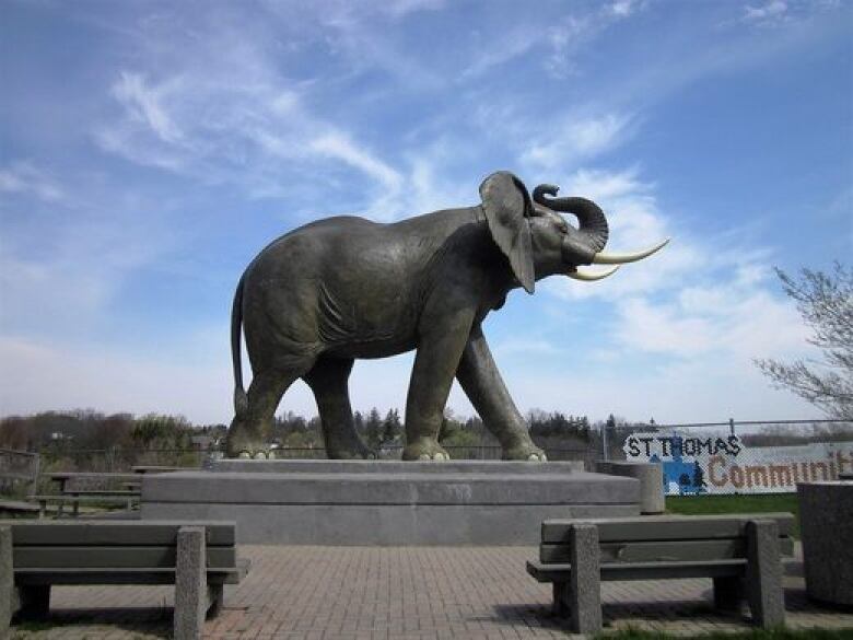 A large statue of an elephant, photographed in silhouette with a blue sky. 