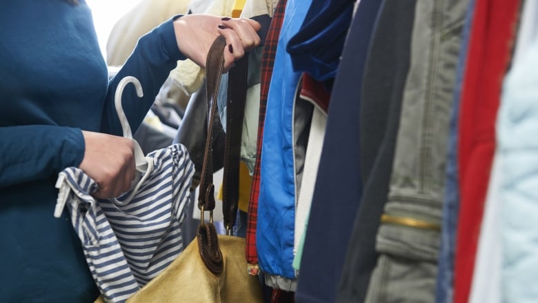 A woman puts an item of clothing in her purse in a store. 