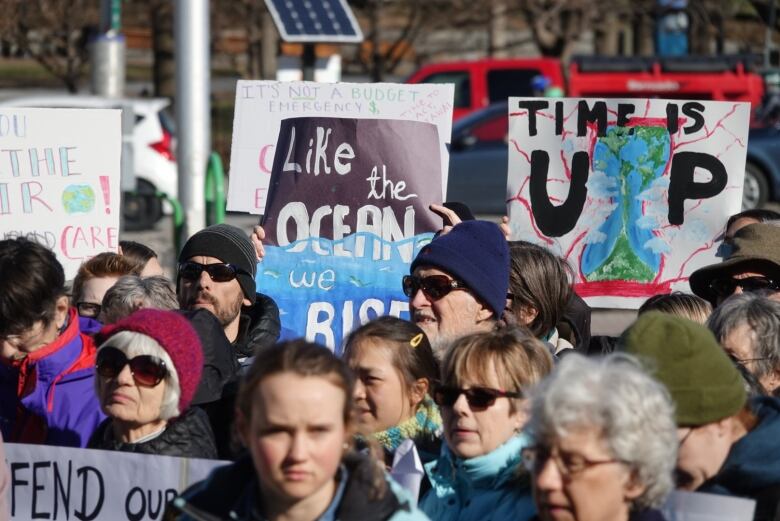 A group of people hold up homemade signs warning about climate change