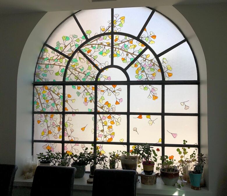 An arched window features a delicate painted pattern of multi-coloured leaves.