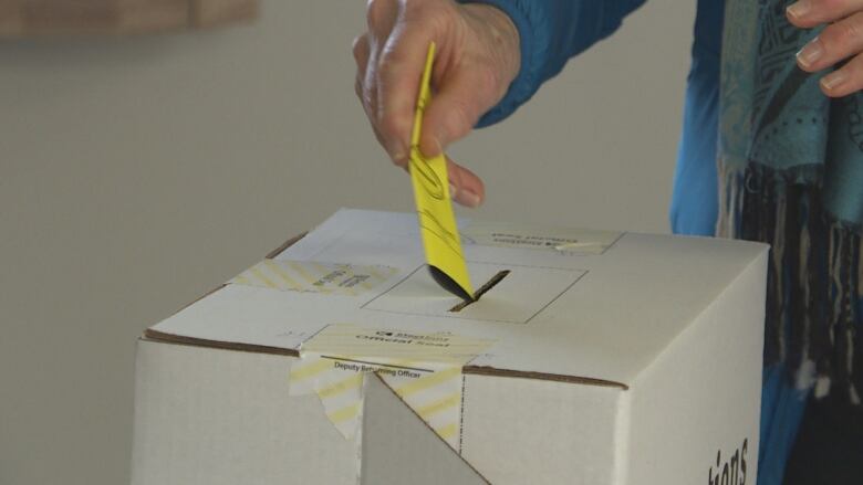 A person putting their ballot into a ballot box during the 2019 P.E.I. election.