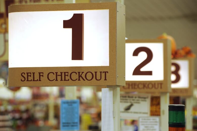 Signs indicating where the self-checkouts are in a store. 