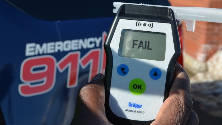 A police officer holds a breath analyzer.