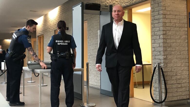 A man in a suit walking through the hall of a courthouse.