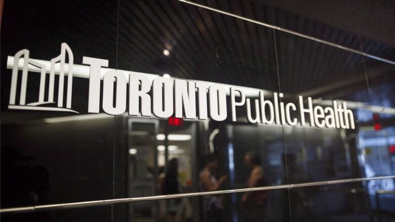 A sign on a wall with white lettering against a black wall that says Toronto Public Health.