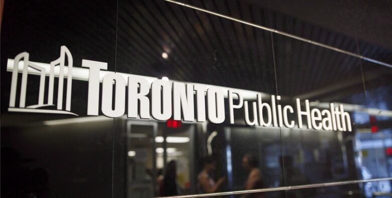 A sign on a wall with white lettering against a black wall that says Toronto Public Health.