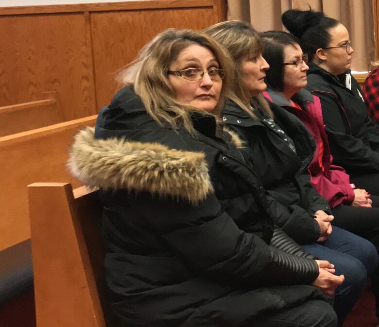 A group of people sit in a courtroom. 