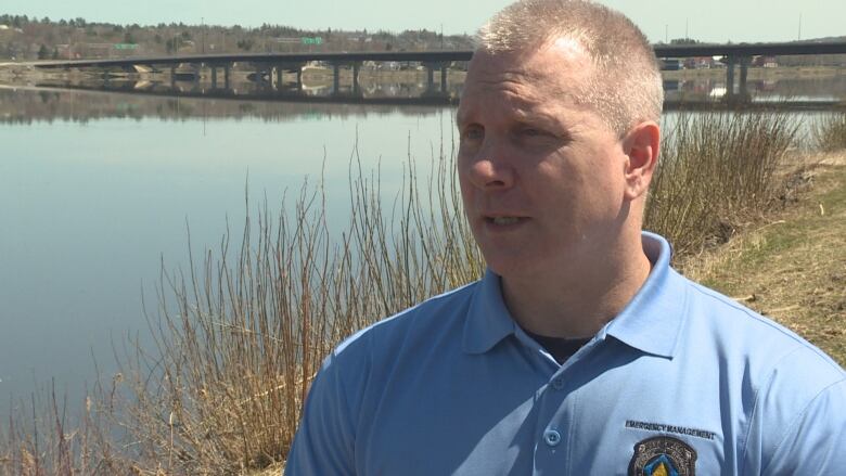 A man in a blue polo standing next to a body of water