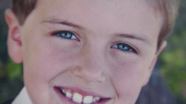 A close-up portrait of a smiling boy with freckles.