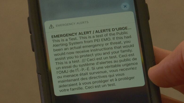 A photo of a mobile phone screen showing emergency alert text that reads: EMERGENCY ALERT. This is a test. This is a test of the Public Alerting System from PEI EMO.