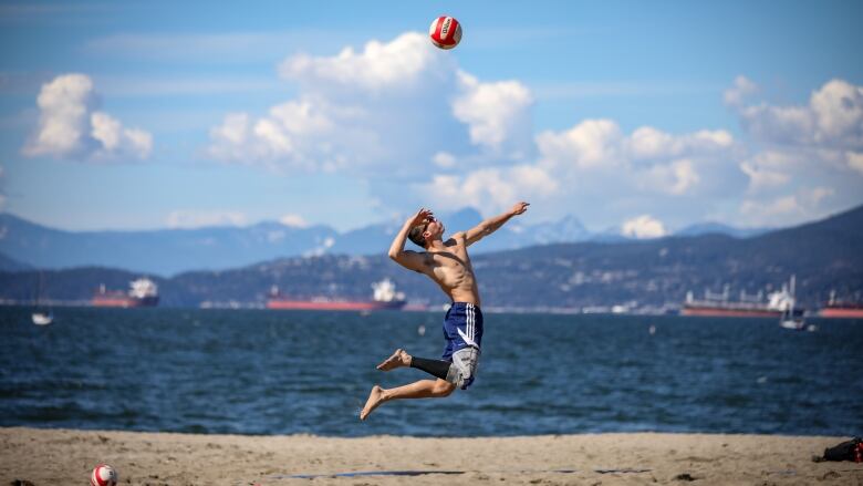 A man jumps to serve a volleyball