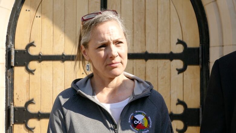 A woman stands in front of a chruch door.