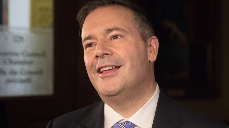 A smiling man dressed in a suit and tie.