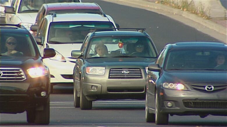 Seven cars can be seen driving on the road. 