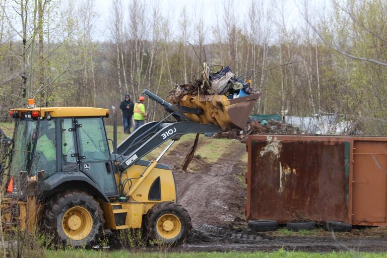 A bulldozer scooping material into a dumpster