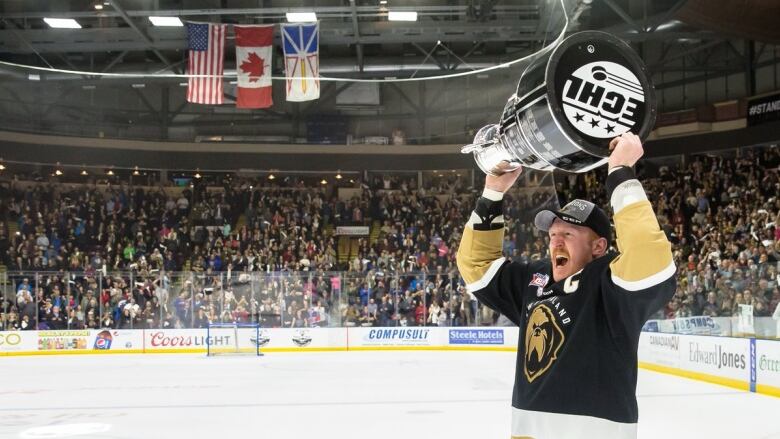 A hockey player holding a trophy over his head. 