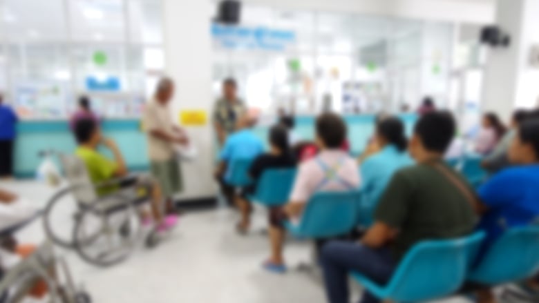 A blurred image of a busy hospital waiting room.