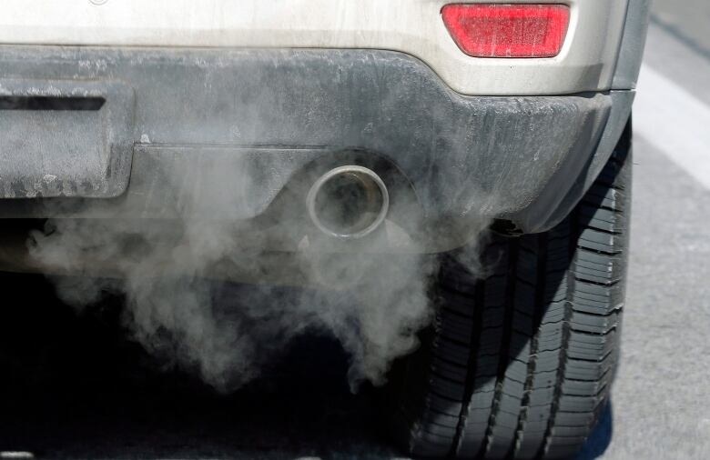 Close-up shot of a silver car tailpipe with exhaust.