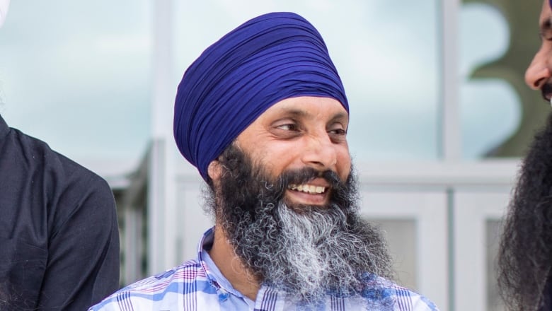 A group of Sikh men speak informally to each other for a posed photograph.