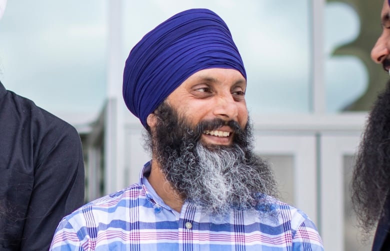 A group of Sikh men speak informally to each other for a posed photograph.