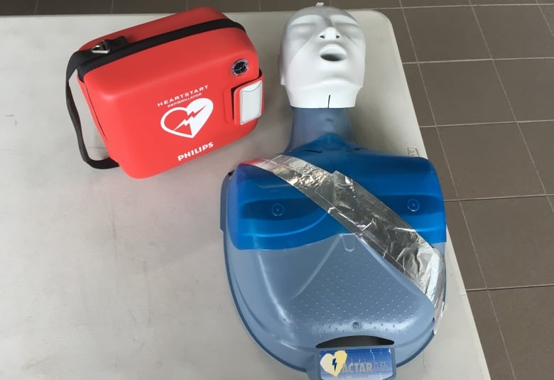 An AED device next to a dummy used for CPR practice