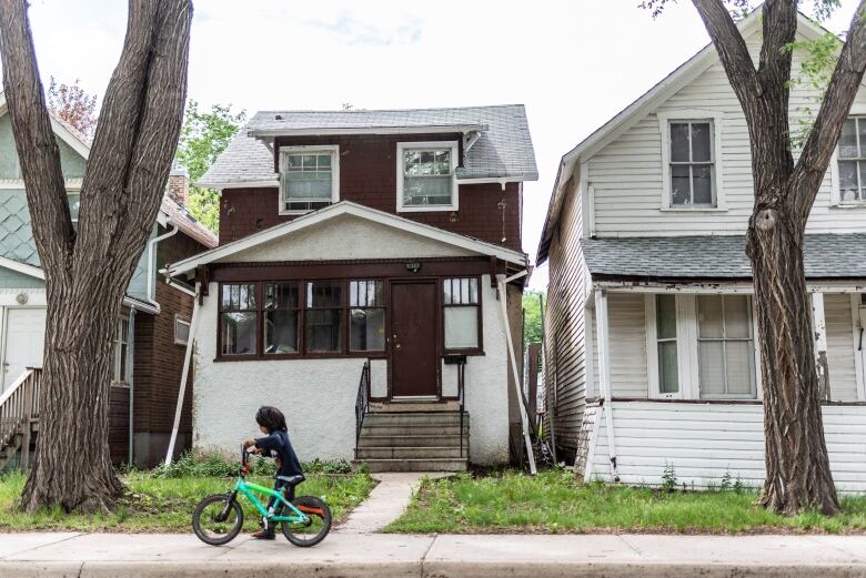 A boy pushes his bike by the former home of Tamra Keepness at 1843 Ottawa St. in Regina, Saskatchewan on Thursday June 27, 2019. Five-year-old Keepness went missing from her home in July 2004. 