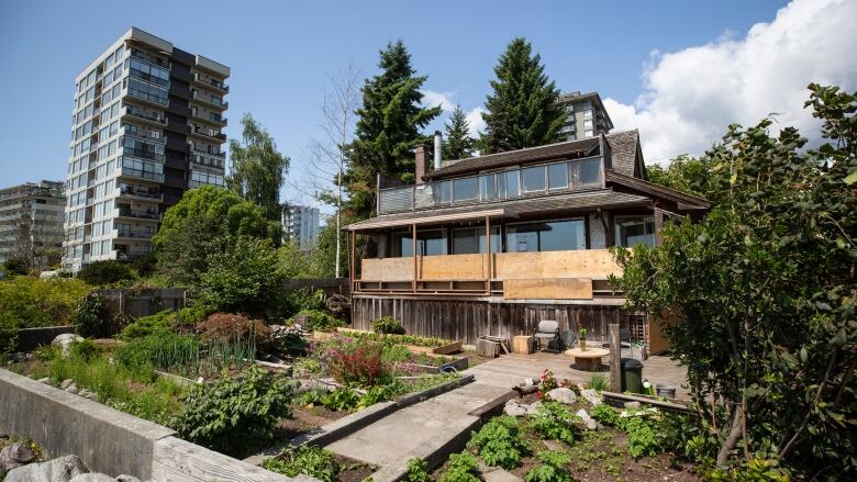 A three-storey building, with some wooden boards in front of it, stands behind a tiny garden.