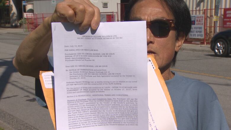 Ron Lee, a pre-sale buyer, holds up his notice to terminate from Anderson Square Holdings. 