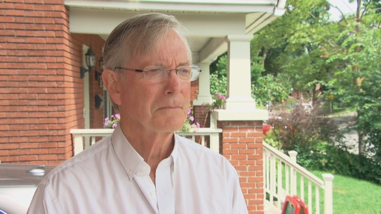 A man, who appears to be in a suburban neighbourhood, looks in the distance.