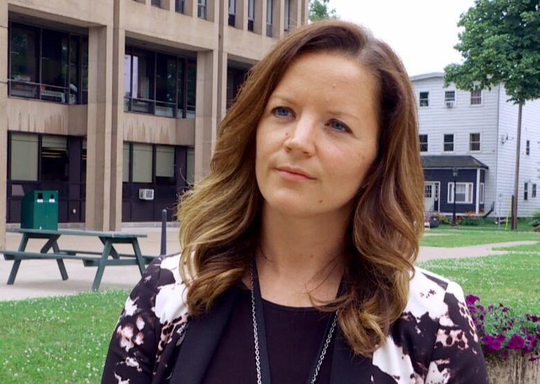 A woman looks at the camera during an interview while standing outside.